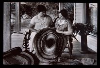 Women displaying braided rug. Black and white photo. 
